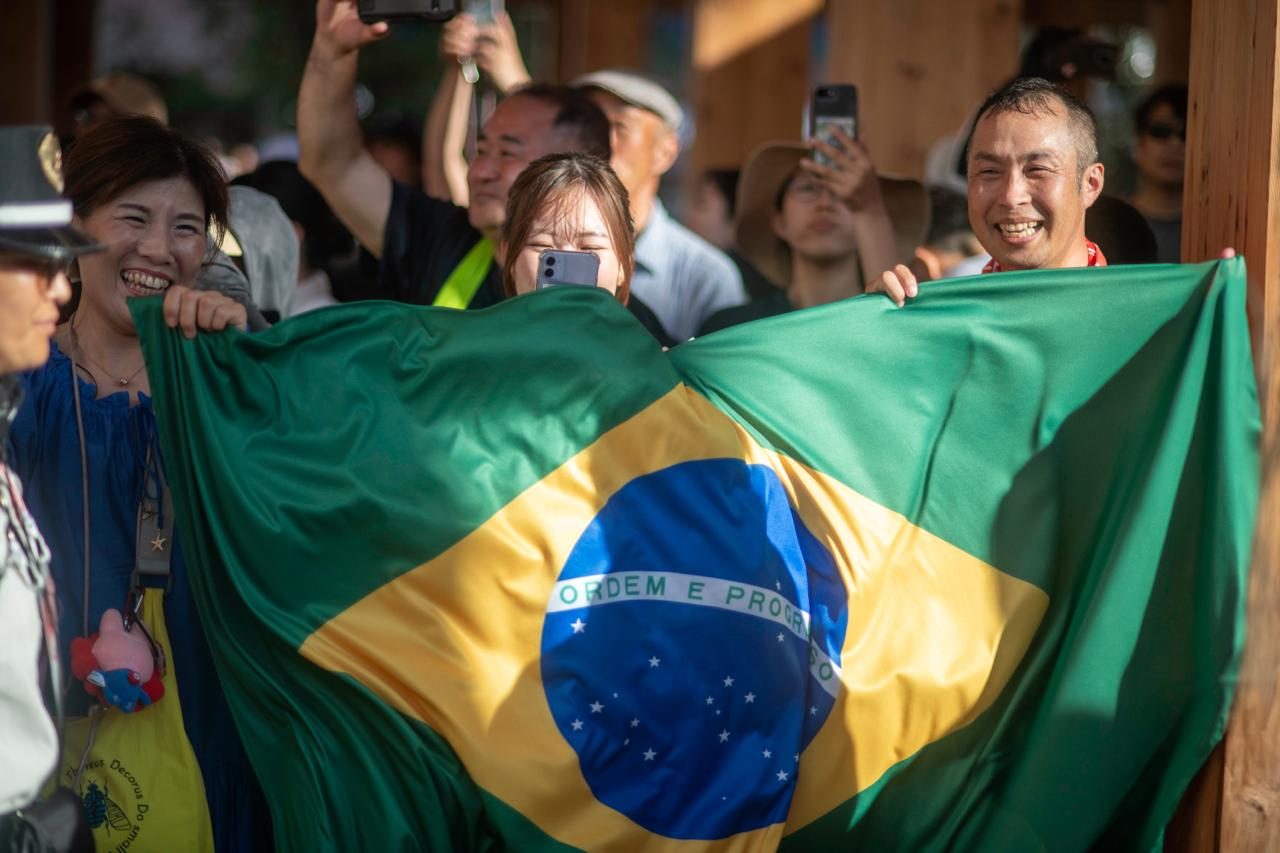 Pessoas segurando a bandeira do Brasil na Expo Osaka